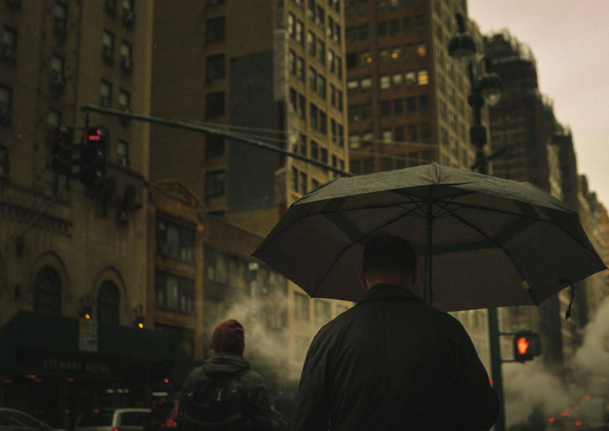 Persona con paraguas caminando por una calle de Nueva York bajo la lluvia